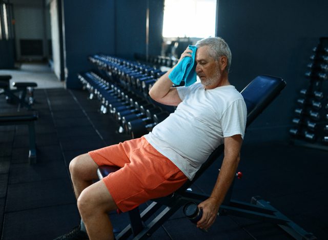 Tired Older Man Sitting On Workout Bench During Workout