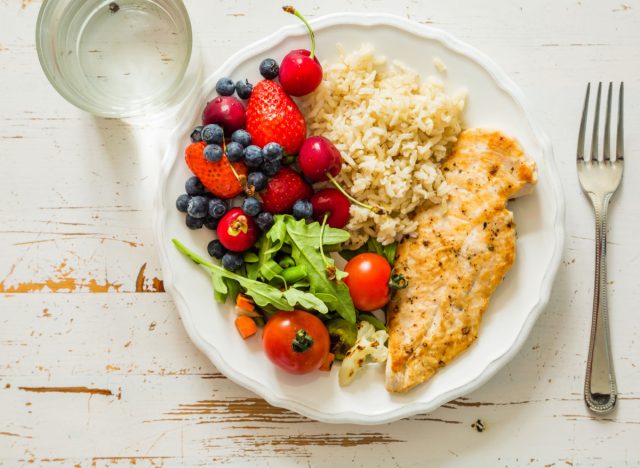 portioned plate with chicken, rice, fruit and salad