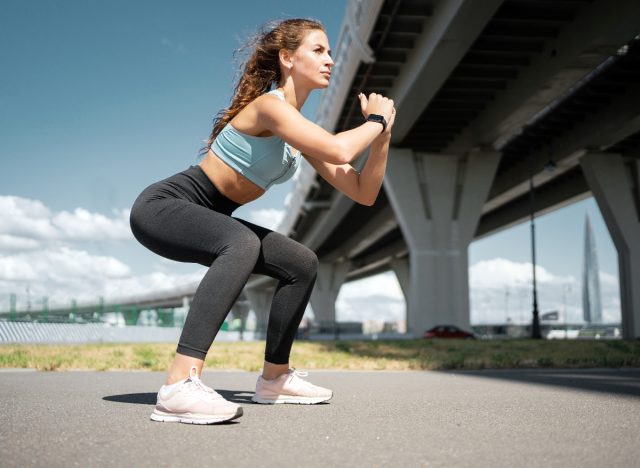 woman is doing squats exercise outdoors, workout concept to reduce dangling belly fat