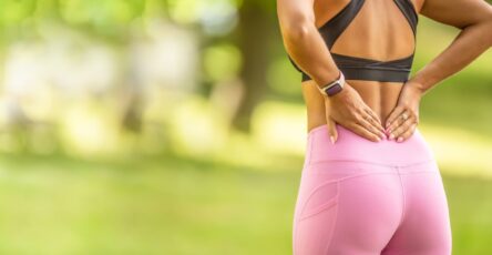 a photo of a woman wearing gym kit holding her back from sciatic nerve pain