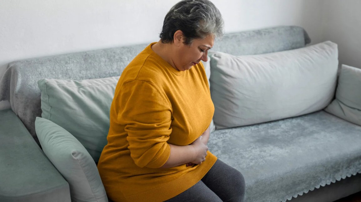 A woman sitting on a couch seems to be in pain.